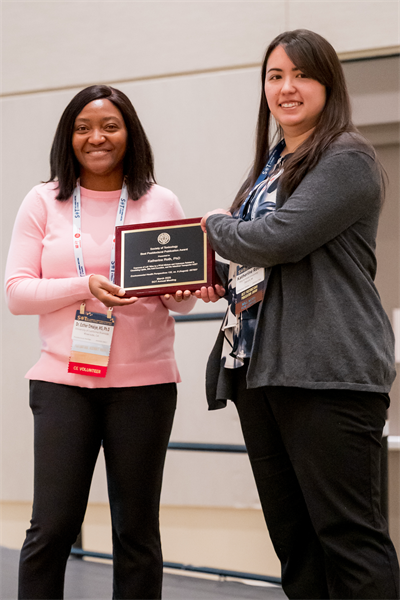 Two women holding an award plaque smiling at the camera.